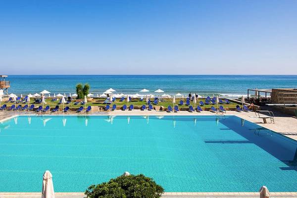 Außenpool des Kernos Beach Hotel mit Blick auf das Meer und Sonnenliegen.