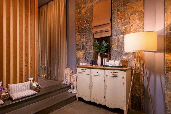 Innenansicht des Kernos Beach Hotel & Bungalows mit Steinwand, Holzelementen und weißem Sideboard.