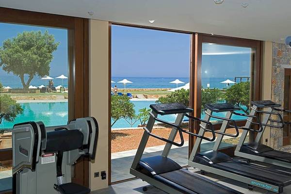 Fitnessgeräte in der Anlage des Kernos Beach Hotel mit Blick auf den Pool und das Meer.