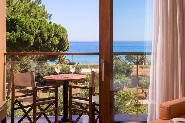 Terrasse mit Meerblick im Kernos Beach Hotel mit Tisch, Stühlen und sommerlicher Dekoration.