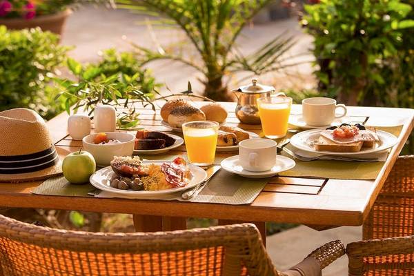 Frühstück auf einem Tisch im Garten des Kernos Beach Hotel & Bungalows mit verschiedenen Speisen und Getränken.