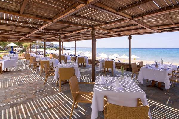 Terrasse des Kernos Beach Hotel mit Blick auf das Meer und gedeckten Tischen.