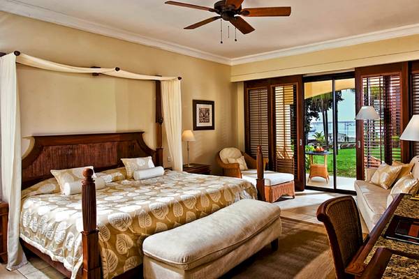 Schlafzimmer im Maritim Resort & Spa Mauritius mit einem großen Bett, Nachttischen, einem Deckenventilator und einer Terrasse.