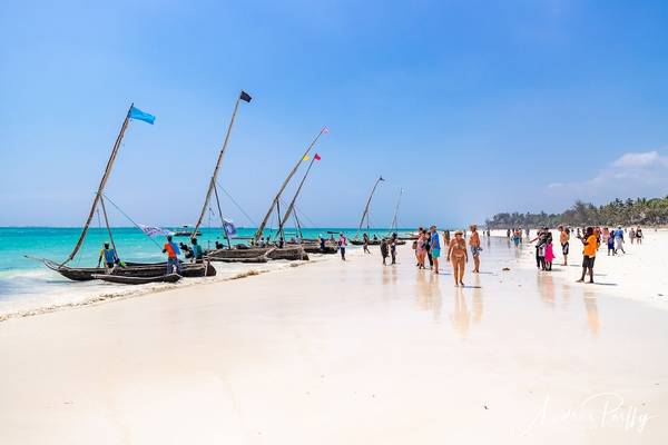 Strand mit Besuchern und traditionellen Fischerbooten im Baobab Beach Resort & Spa