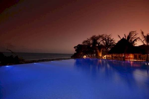Pool im Baobab Beach Resort & Spa bei Nacht mit Beleuchtung und Blick auf den Ozean.