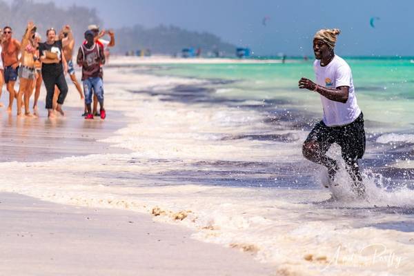 Mann läuft am Strand vor Publikum und sprüht Wasser auf