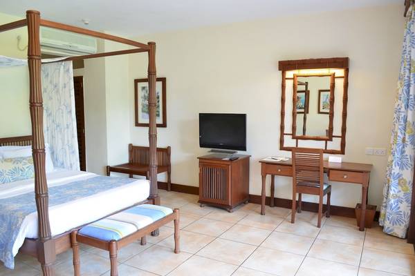 Ein Hotelzimmer im Baobab Beach Resort & Spa mit einem Himmelbett, Fernseher und Schreibtisch.