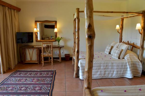 Doppelbett-Zimmer im Baobab Beach Resort & Spa mit einem Holzbett, einem Schreibtisch und einem Fernseher.