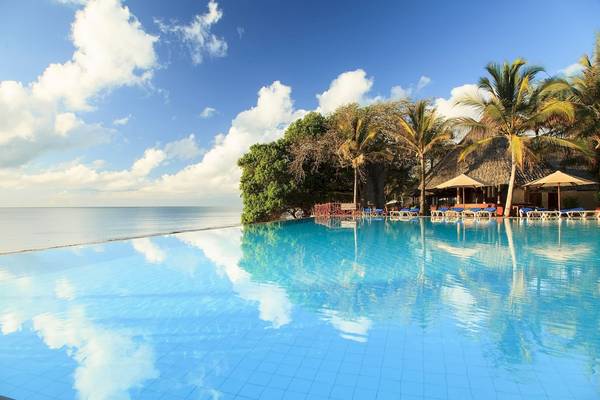 Außenpool am Strand des Baobab Beach Resort & Spa mit Sonnenliegen und Palmen