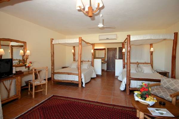 Doppelbettzimmer im Baobab Beach Resort & Spa mit zwei Betten, Holzmöbeln und einem Tisch mit Früchten.