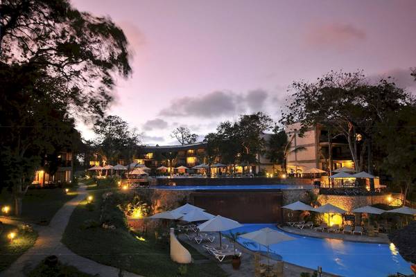 Abendansicht des Pools im Baobab Beach Resort & Spa mit vielen geöffneten Sonnenschirmen.