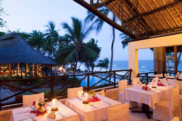 Außenbereich des Baobab Beach Resort & Spa mit gedeckten Tischen, Blick auf das Meer und Palmen.