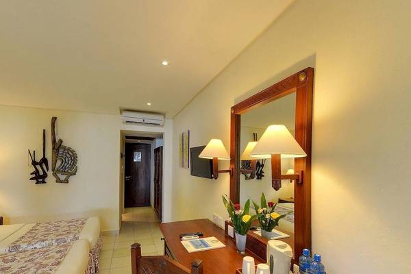 Ein Zimmer im Baobab Beach Resort & Spa mit zwei Betten, einem Schreibtisch und einem Spiegel.