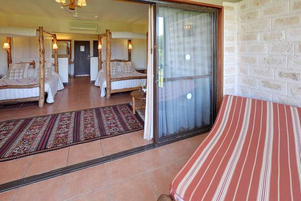 Zimmer im Baobab Beach Resort & Spa mit offenen Schiebetüren, zwei Doppelbetten und einem Tisch.