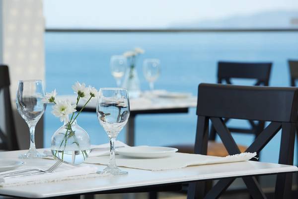 Tisch im Restaurant mit Blick auf das Meer und Blumenvase auf dem Tisch