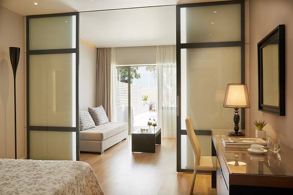 Schlafzimmer im MarBella Corfu Hotel mit Doppelbett, Sofa, Schreibtisch und Lampen.