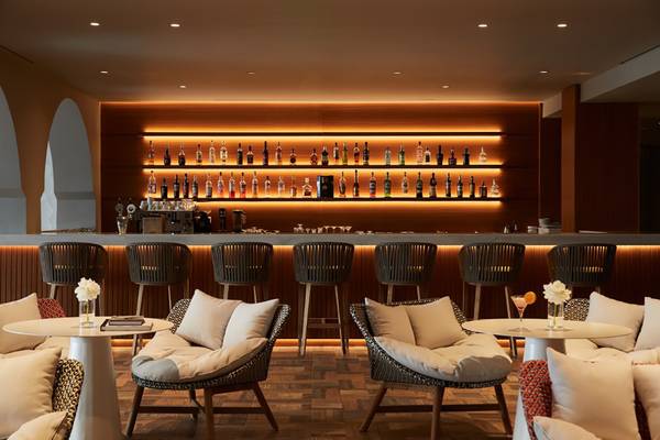 Hotelbar im MarBella Corfu mit Barhockern, Tischen und einer gut bestückten Bar.