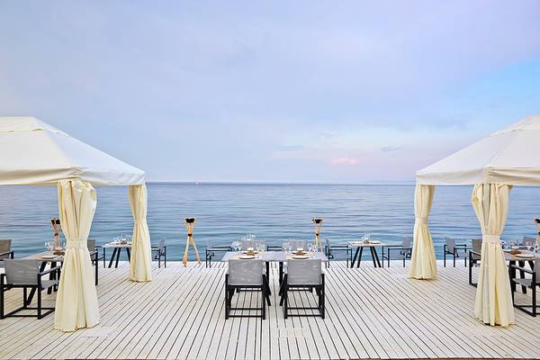 MarBella Corfu Hotel Terrasse mit Meerblick und zwei gedeckten Tischen unter weißen Vorhängen.