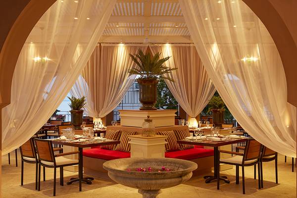 Innenbereich des MarBella Corfu Hotels mit gedeckten Tischen, weichen Vorhängen und Pflanzen.