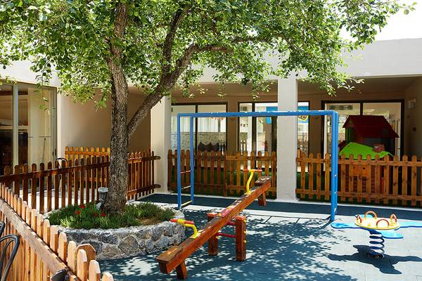 Spielplatz im Freien des MarBella Corfu Hotels mit Schaukeln und Spielhaus.
