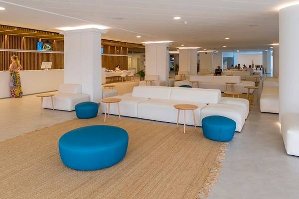 Lobby des Vibra Algarb Hotels mit weißen Möbeln, blauen Hockern und einer Rezeption.
