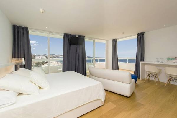 Schlafzimmer im Vibra Algarb Hotel mit Meerblick, weißer Bettwäsche, weißem Sofa und großen Fenstern.