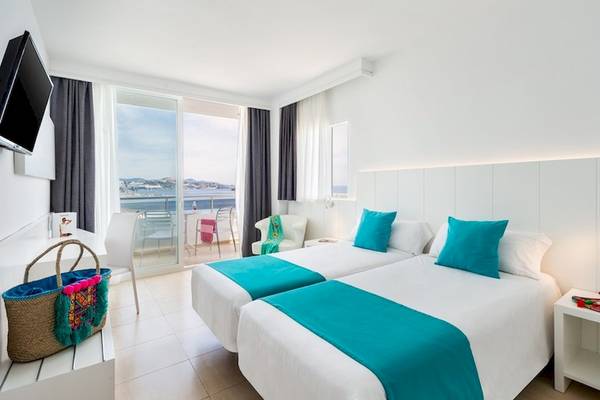Doppelzimmer im Vibra Algarb Hotel mit Meerblick, zwei Betten, türkisen Kissen, Balkon mit Stühlen und Tisch.