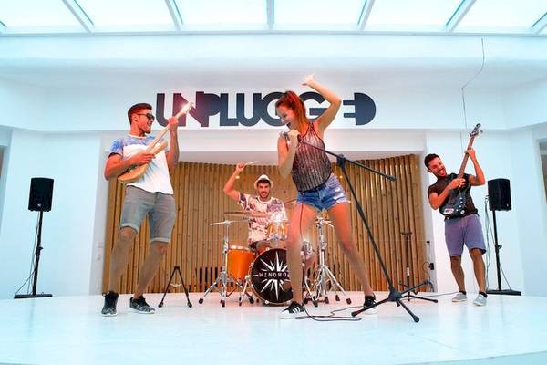 Eine Band spielt auf der Bühne im Vibra Algarb Hotel, mit einer Frau, die singt, und drei Männer, die Gitarre, Schlagzeug und Bass spielen.