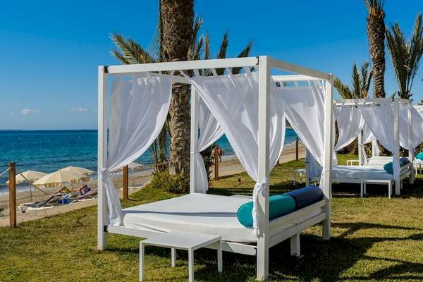 Mehrere weiße Sonnenbetten auf der Wiese neben dem Strand im Vibra Algarb Hotel.