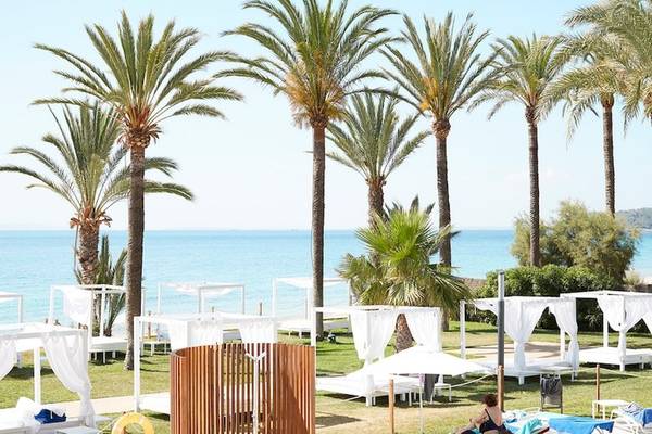 Außenbereich des Vibra Algarb Hotels mit Palmen, weißen Sonnenschirmen und Blick auf das Meer.