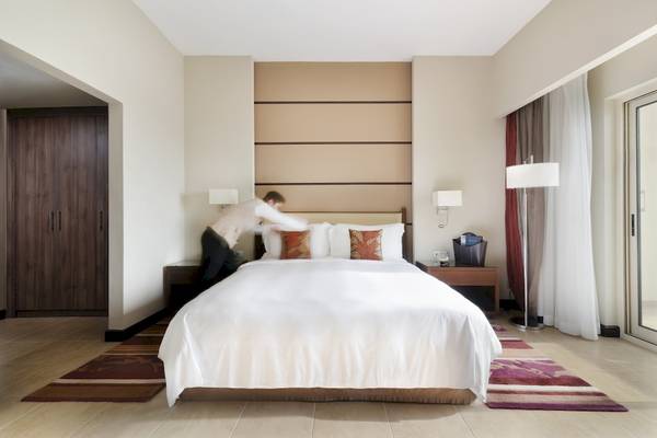 Zimmer im Khalidiya Palace Rayhaan by Rotana mit Bett, das gerade zugedeckt wird