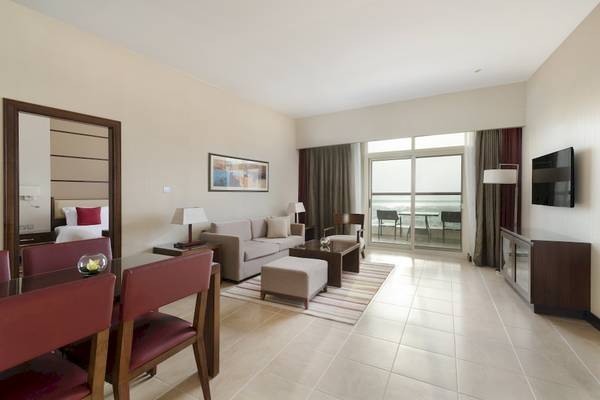 Wohnbereich der Khalidiya Palace Rayhaan Suite mit Sofa, Tisch, Stühlen und Fernseher.