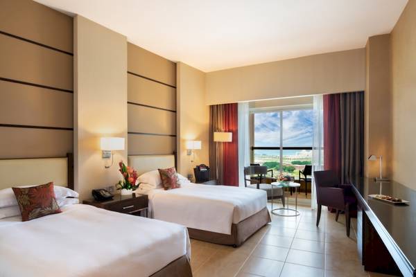 Doppelzimmer im Khalidiya Palace Rayhaan by Rotana mit zwei Betten, Fenstern und Aussicht.