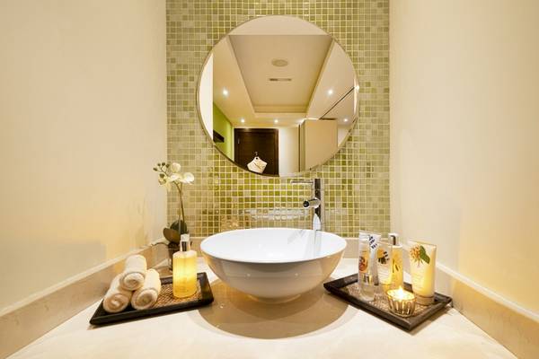 Badezimmer im Khalidiya Palace Rayhaan by Rotana mit grünen Fliesen, weißem Waschbecken und Kerzen.