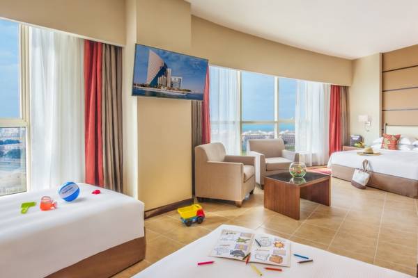 Kinderzimmer im Khalidiya Palace Rayhaan by Rotana mit zwei Betten, Spielzeug und einem Fernseher.