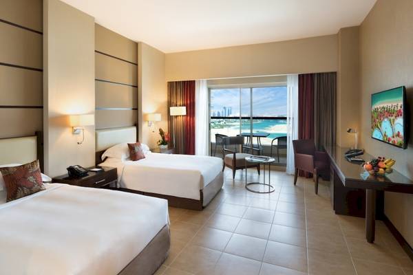 Zimmer im Khalidiya Palace Rayhaan mit zwei Betten und Meerblick.