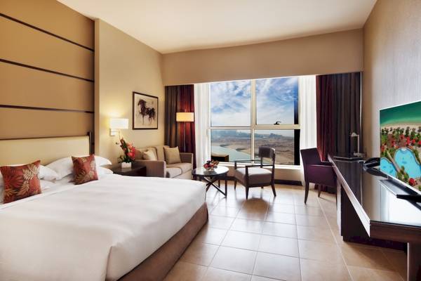 Khalidiya Palace Rayhaan by Rotana Hotelzimmer mit großem Bett und Aussicht auf den See.