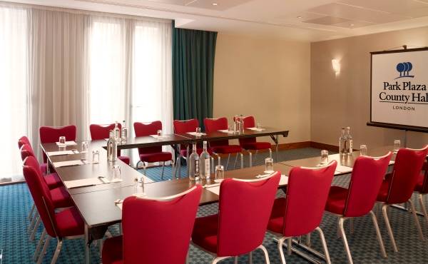Konferenzraum im Park Plaza County Hall London mit roten Stühlen und Tischen.