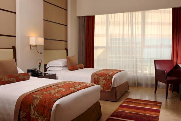 Doppelzimmer im Khalidiya Palace Rayhaan by Rotana mit zwei Betten, einem Schreibtisch und einem Fenster.