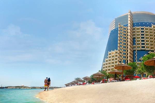 Paar am Strand vor dem Khalidiya Palace Rayhaan by Rotana Hotel