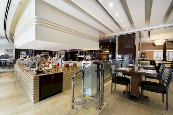 Innenbereich des Khalidiya Palace Rayhaan by Rotana Hotel mit Buffet und Tischen.