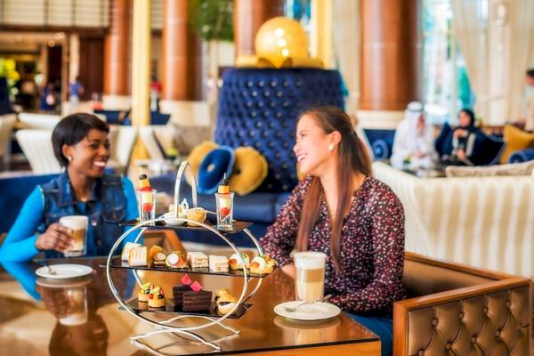 Zwei Frauen im Hotelcafe von Khalidiya Palace Rayhaan by Rotana, die lächeln und einen Nachtisch genießen.
