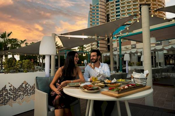 Ein Paar sitzt auf der Terrasse von Khalidiya Palace Rayhaan by Rotana und isst.