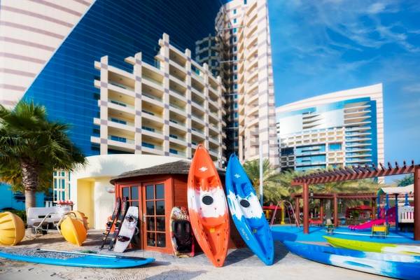 Außenbereich des Khalidiya Palace Rayhaan by Rotana mit Kajaks und Gebäuden im Hintergrund.