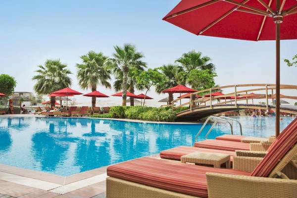 Poolszene im Khalidiya Palace Rayhaan by Rotana mit Sonnenschirmen und Liegestühlen.