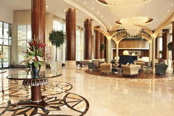 Lobby des Khalidiya Palace Rayhaan by Rotana Hotel mit Kronleuchtern, Blumenvase und Sitzbereichen.