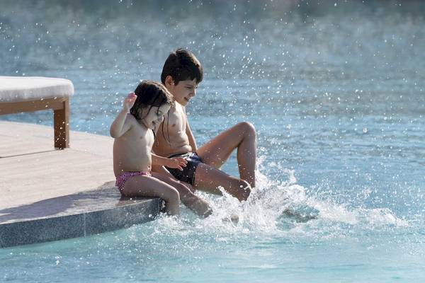 Zwei Kinder springen im InterContinental Ras Al Khaimah Mina Al Arab Resort & Spa ins Schwimmbecken.