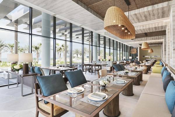 Innenraum des Restaurants im InterContinental Ras Al Khaimah Mina Al Arab mit großen Fenstern, modernen Möbeln und Meeresblick.