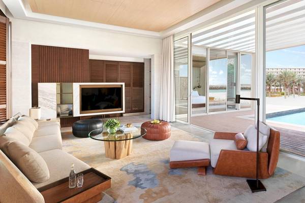 Wohnzimmer des InterContinental Ras Al Khaimah mit Möbeln, Fernseher und Blick auf den Pool.