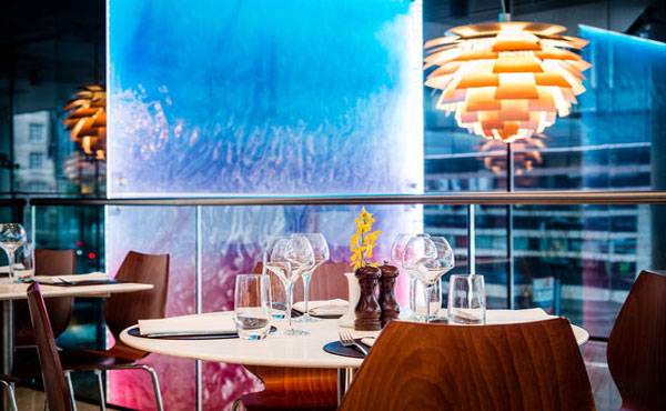 Innenansicht des Restaurants im Park Plaza County Hall London mit Tisch, Gläsern und blauer Wand